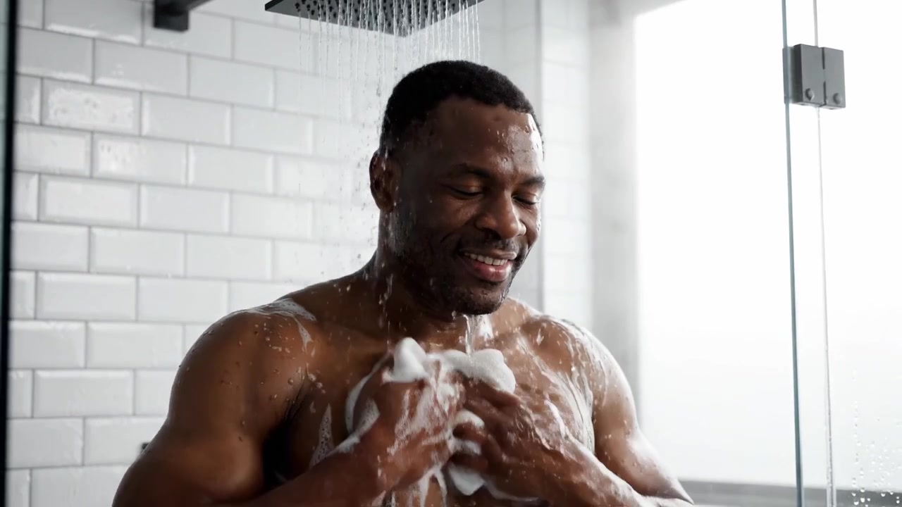 Refreshing Shower Experience: A Man Enjoys a Moment of Tranquility Under the Shower, Experiencing Warm Water and Foam for Rejuvenation and Relaxation