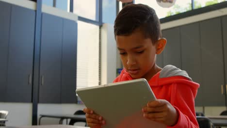 Low-angle-view-of-attentive-Asian-schoolboy-studying-with-digital-tablet-in-classroom-at-school-4k