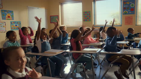 diverse elementary school students raising hands eagerly in classroom