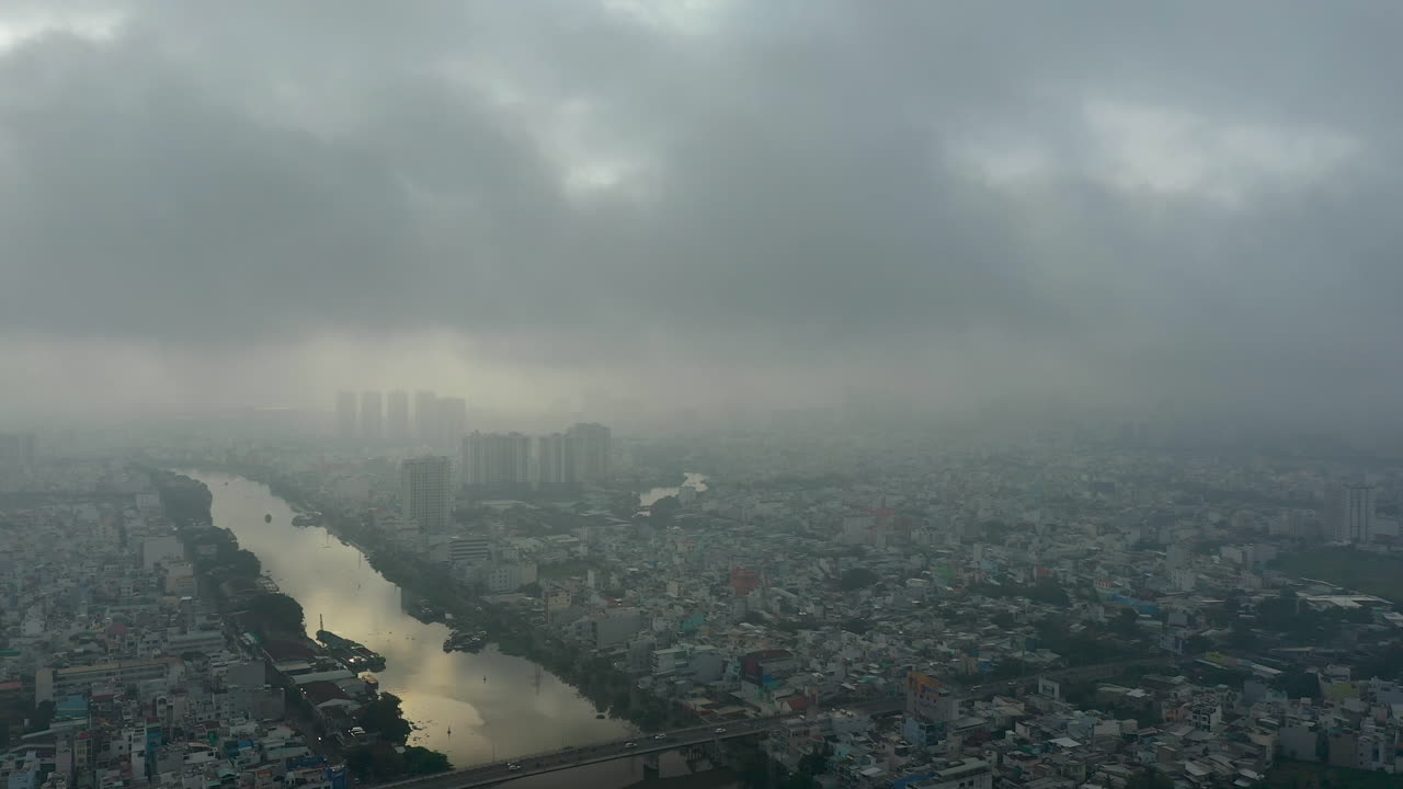 saigón, ciudad de ho chi minh, imágenes de drones de la madrugada de vietnam volando en una gran órbita alrededor del canal sobre los distritos cuatro, siete y el horizonte de la ciudad a través de una densa niebla y la contaminación del aire típica del sudeste asiático