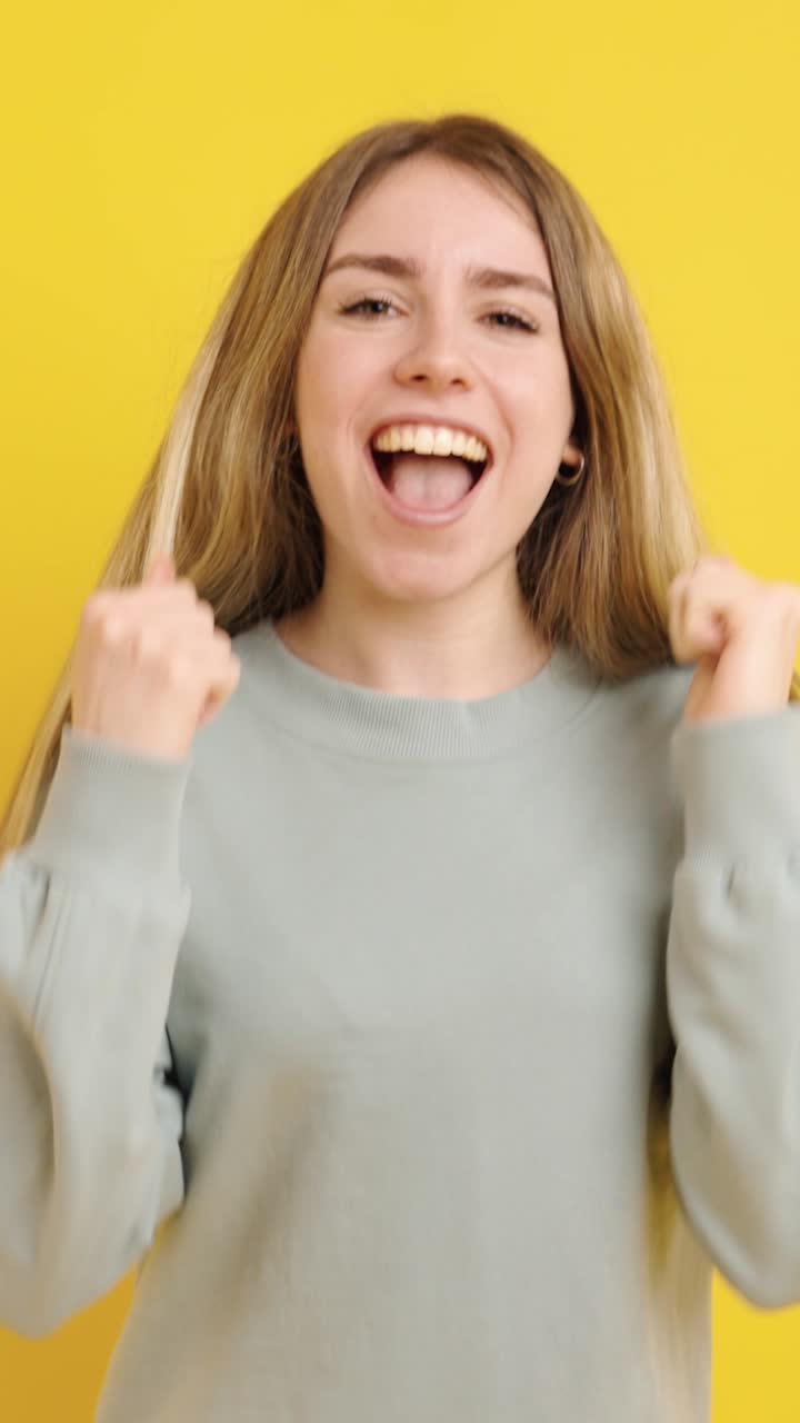 Young woman expressing excitement on yellow background