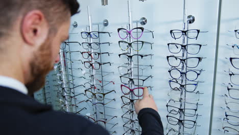 man shopping for glasses in store. handsome man measures glasses for vision in store