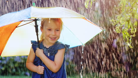 carefree little girl under a colored umbrella hiding from the rain