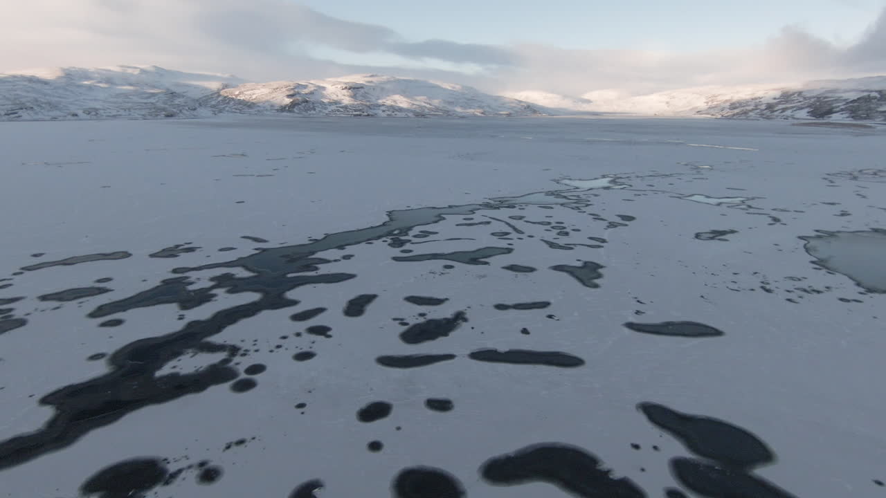 Snowy mountains at sunrise, frozen lake