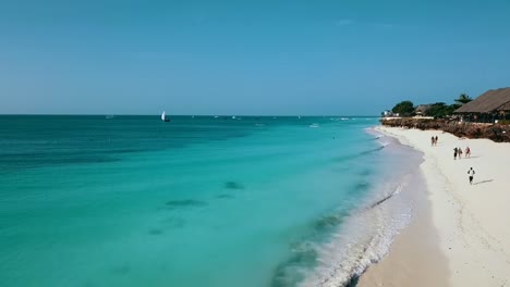 wonderful aerial flight fly forwards drone shot on coastline wave white sand beach bikini girls