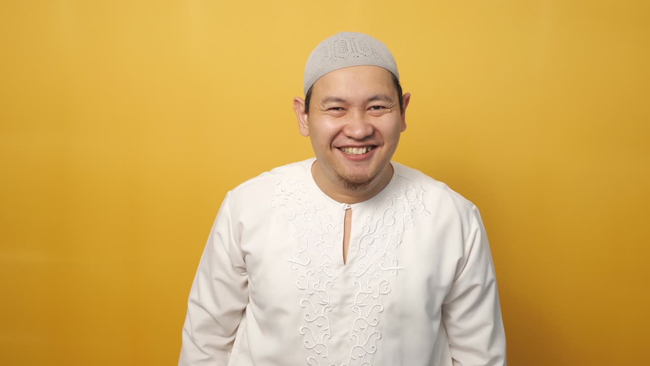 성공한 행복한 무슬림 남자가 울부고 노란색 배경 위에서 승리의 몸짓을 보여줍니다.