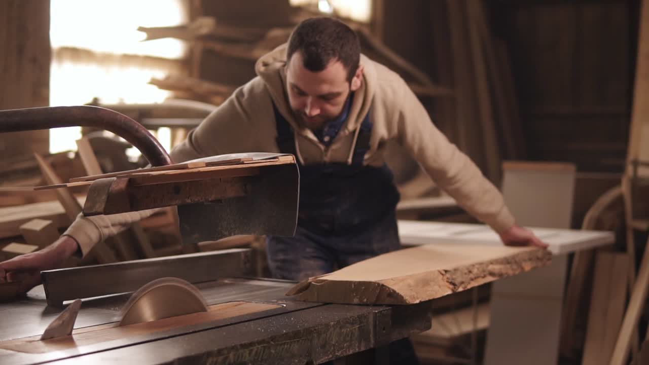 The circular saw in process. The carpenter cuts the edges of a large piece of wood . Carpenter's workshop