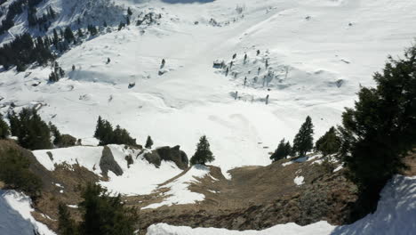 drone flying over mountain ridge, revealing beautiful valley covered in snow