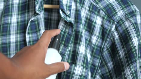 man spraying deodorant on a plaid shirt