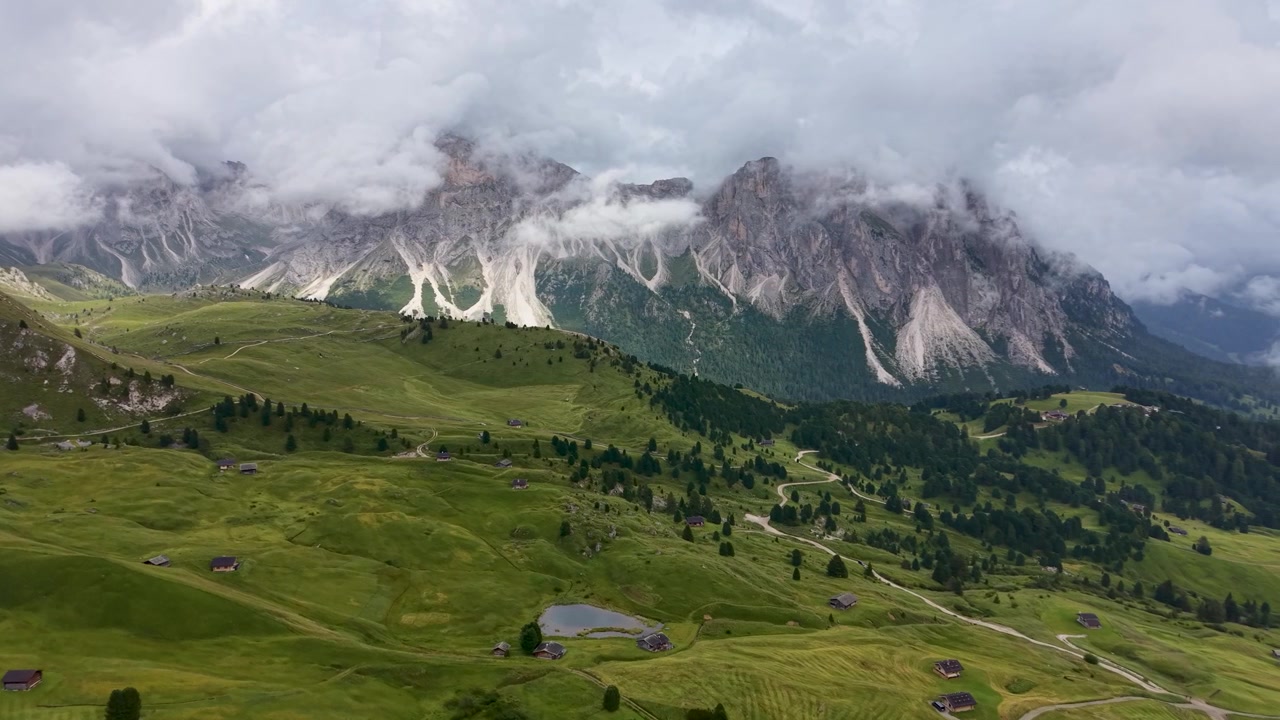Vue par drone des prairies alpines de Seceda avec le massif du Sassolungo partiellement couvert par des nuages spectaculaires dans les Dolomites, Italie.