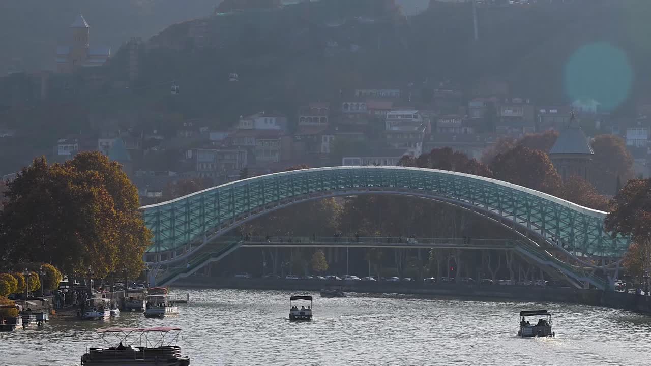 Boats resting on the river near the Bridge of Peace in Tbilisi, capturing a calm moment by the iconic landmark