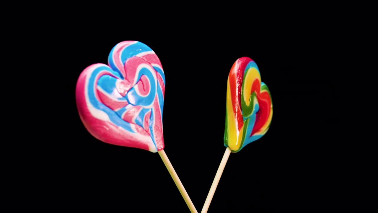 mezcla de piruletas en espiral girando sobre un fondo negro. caramelo caramelo en un palo en forma de corazón