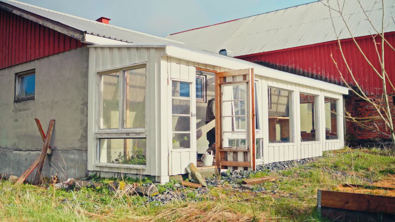 A Man Building And Renovating A Greenhouse In His Yard. Static Shot