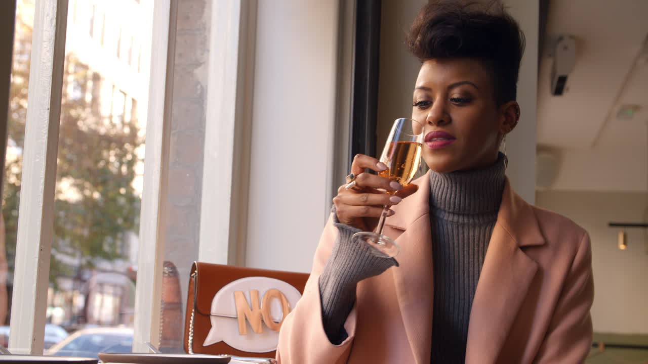 Stylish Woman Sitting In Window Of Bar Enjoying Drink