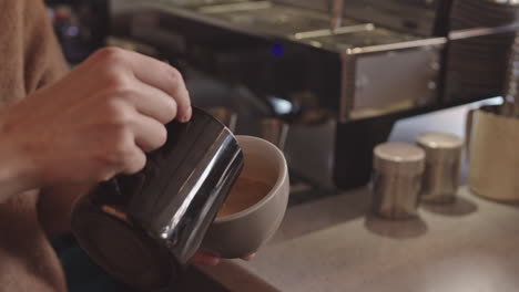 unrecognizable bartender making cappuccino in coffeeshop
