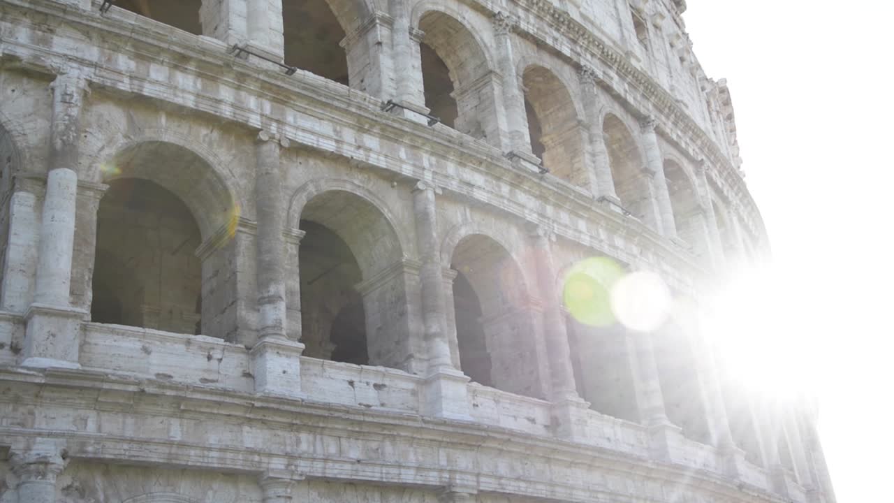 un travelling lento del coliseo en roma, que revela el sol y luego retrocede para ocultarlo