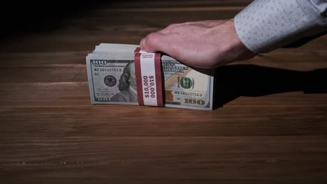 male hands hold three stacks of 10000 us dollar bills on wooden background