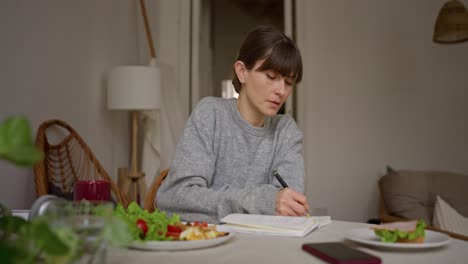 woman writing in a notebook during breakfast