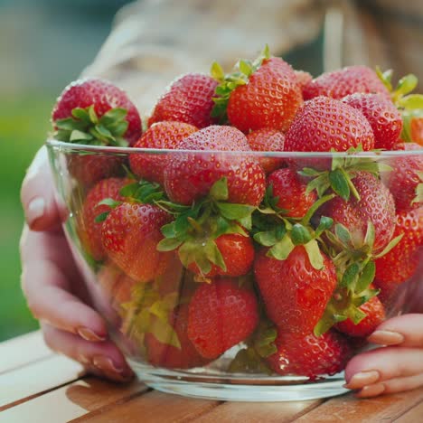 a woman puts a bowl of ripe strawberries on the table 1