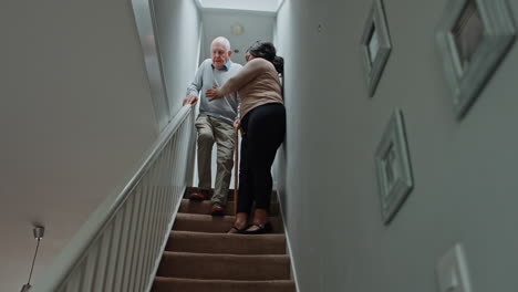 caregiver assisting elderly man on stairs