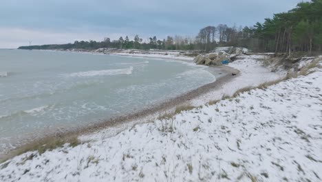 aerial establishing view of abandoned seaside fortification buildings at karosta northern forts on the beach of baltic sea , overcast winter day, wide drone shot moving forward low