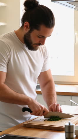 man chopping fresh herbs in a kitchen