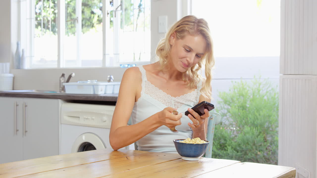 mujer comiendo cereales mientras mira el teléfono inteligente