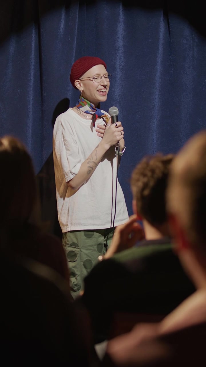 Comica sorridente che si esibisce in stand-up sul palco.