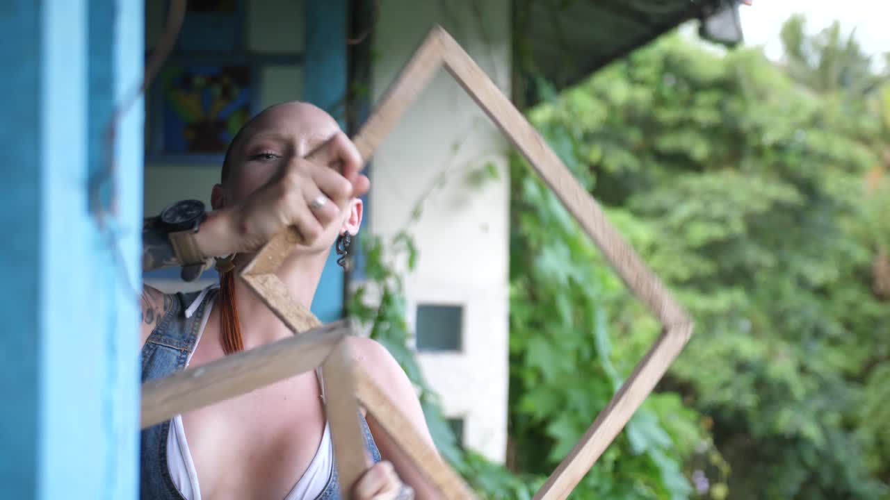 삭발하고 대머리인 젊고 시원해 보이는 여성이 높은 에너지와 강렬한 표정으로 춤추고 움직이고 있습니다.