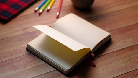 open notebook with pencils on wooden table