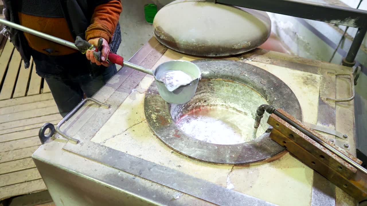 trabajador masculino recogiendo la olla de fundición de moldes de aluminio fundido