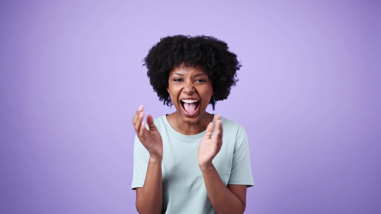 Happy African American Woman Clapping and Laughing on Purple Background