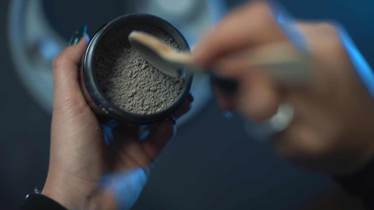 나무 숟가락으로 점토 안면 마스크를 복용