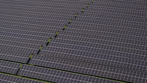 fly over with tilt down on a huge solar power plant with multiple solar panels on a green hill in germany, renewable energy, aerial footage