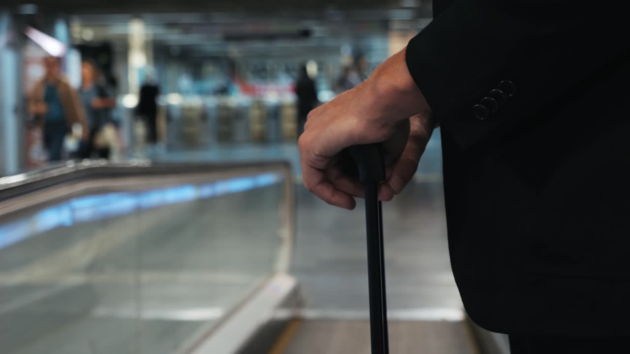 Man in suit with luggage on escalator at airport