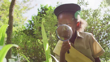 animación de una niña afroamericana en disfraz de explorador usando lupa en el jardín