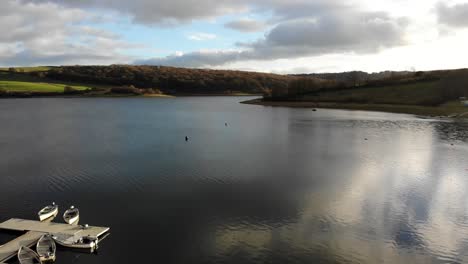 toma aérea hacia atrás del lago wimbleball exmoor uk para revelar barcos amarrados al lado del lago