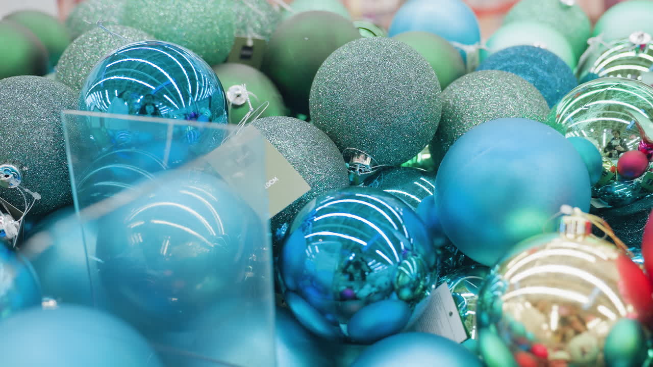 Close-up of vibrant green, blue, and shimmering Christmas ornaments together in a store, reflecting colorful festive lights and creating a joyful holiday shopping atmosphere