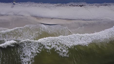 Aerial-looking-down-and-waves-striking-a-sand-beach