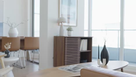 knee level rising shot of the living area in a high ceiling penthouse condominium unit focus from sofa armrest to storage shelf at the back during a sunny day