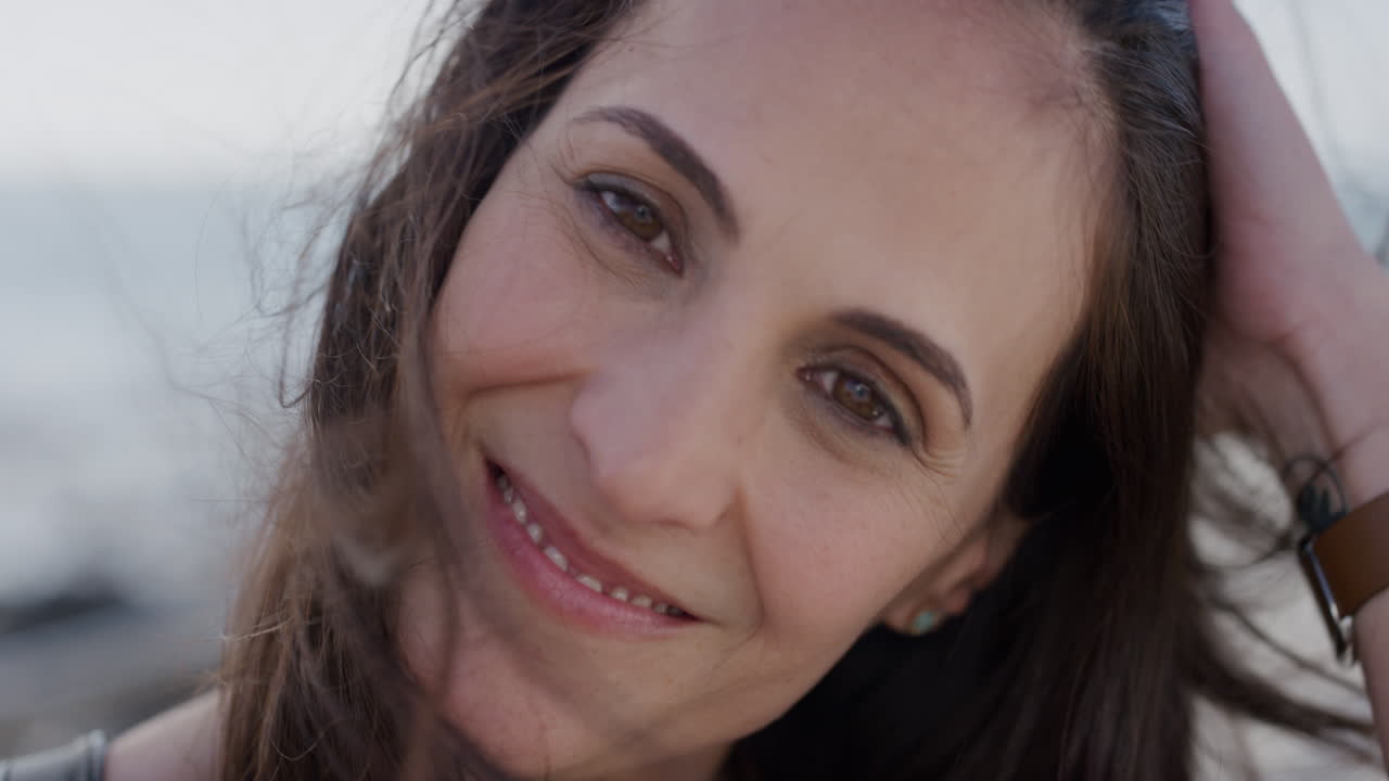 retrato de una hermosa mujer madura sonriendo corriendo con la mano a través del cabello disfrutando de un estilo de vida exitoso en cámara lenta