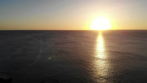 vista aérea de la puesta de sol amarilla dorada sobre el agua del océano hacia el horizonte