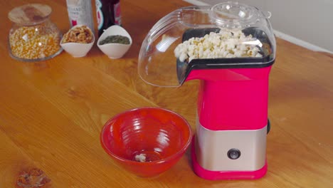 popcorn popping into red bowl from hot air popcorn maker on kitchen counter