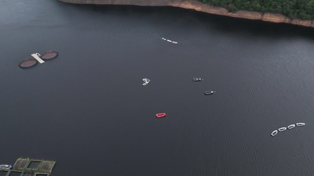 Drone footage captures stationary boats and floating platforms on calm water at Ladybower Reservoir, Hope Valley, under soft natural daylight with smooth camera movement
