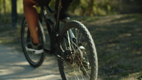 close-up shot of man with bionic leg spinning pedals in forest