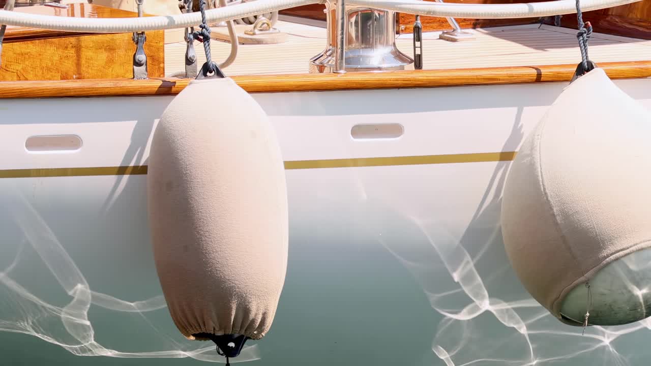 Detailed view of a boat fender with shimmering water reflections on the hull.
