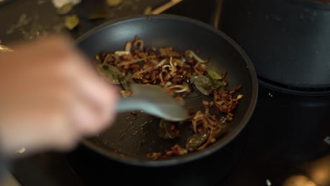 close up of female hands stirring frying pan contents