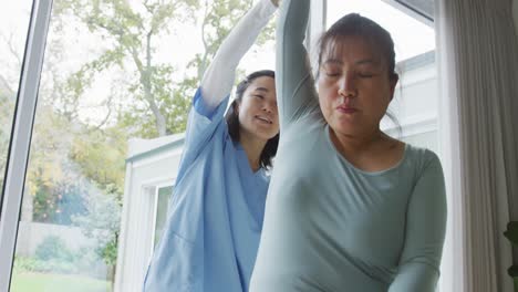 asian female physiotherapist treating female patient at surgery, moving her arm