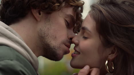 amantes felices besándose en la calle urbana, una mujer mordiendo el labio de su novio al aire libre.