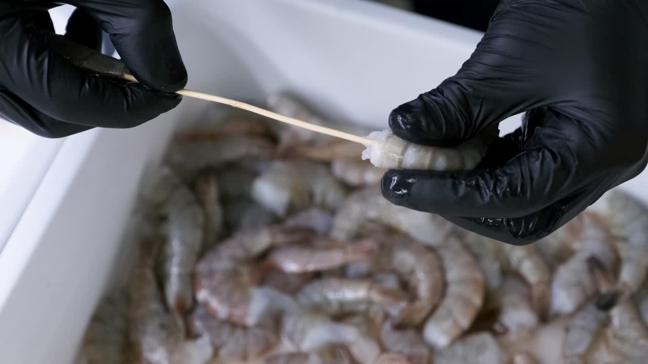 las manos pegan camarones en un palo de madera